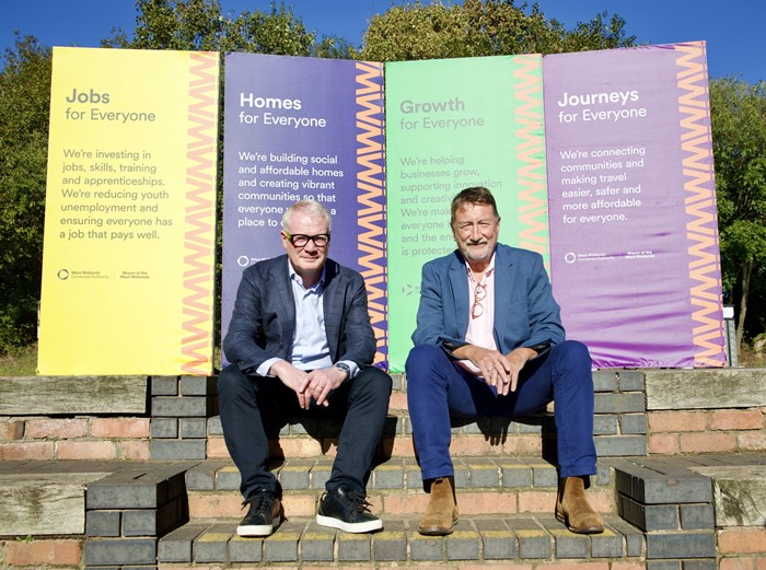 Mayor Richard Parker sitting with film and tv maker Steven Knight in front of four colourful panels setting out mayor's priorities of jobs and skills, homes, economic growth and journeys.