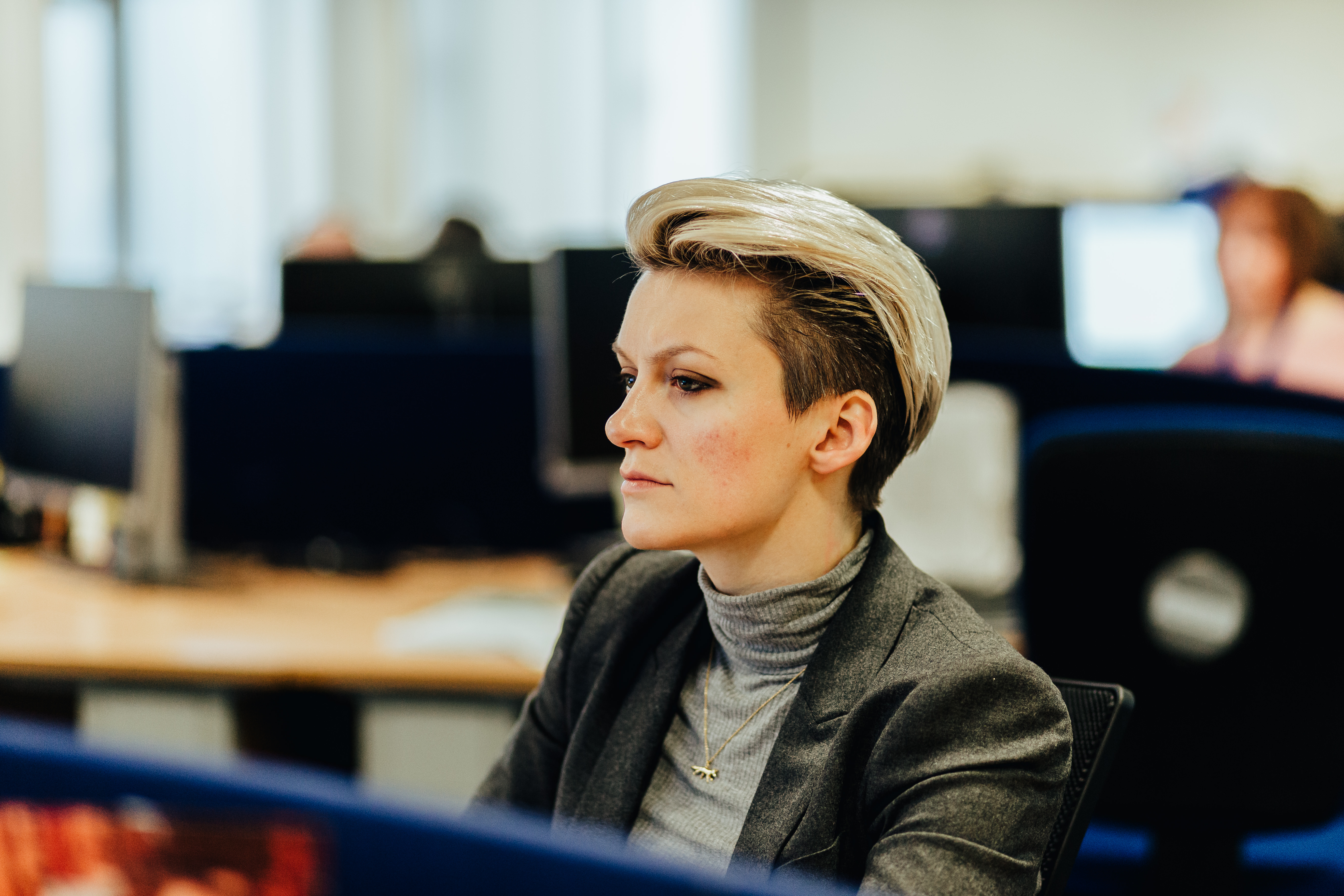 A woman sitting at a desk working on a computer screen