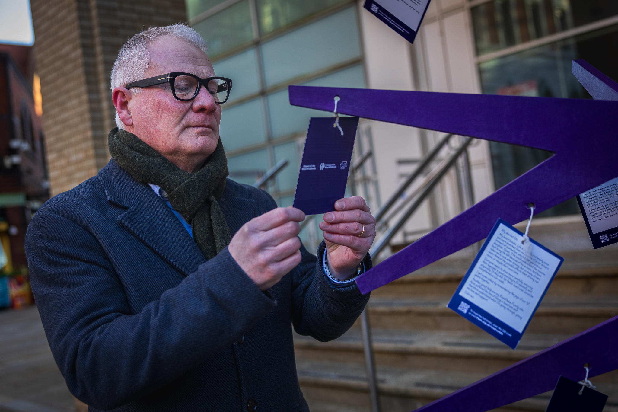 Mayor is reading one of the messages on a piece of card hanging from a purple tree branch