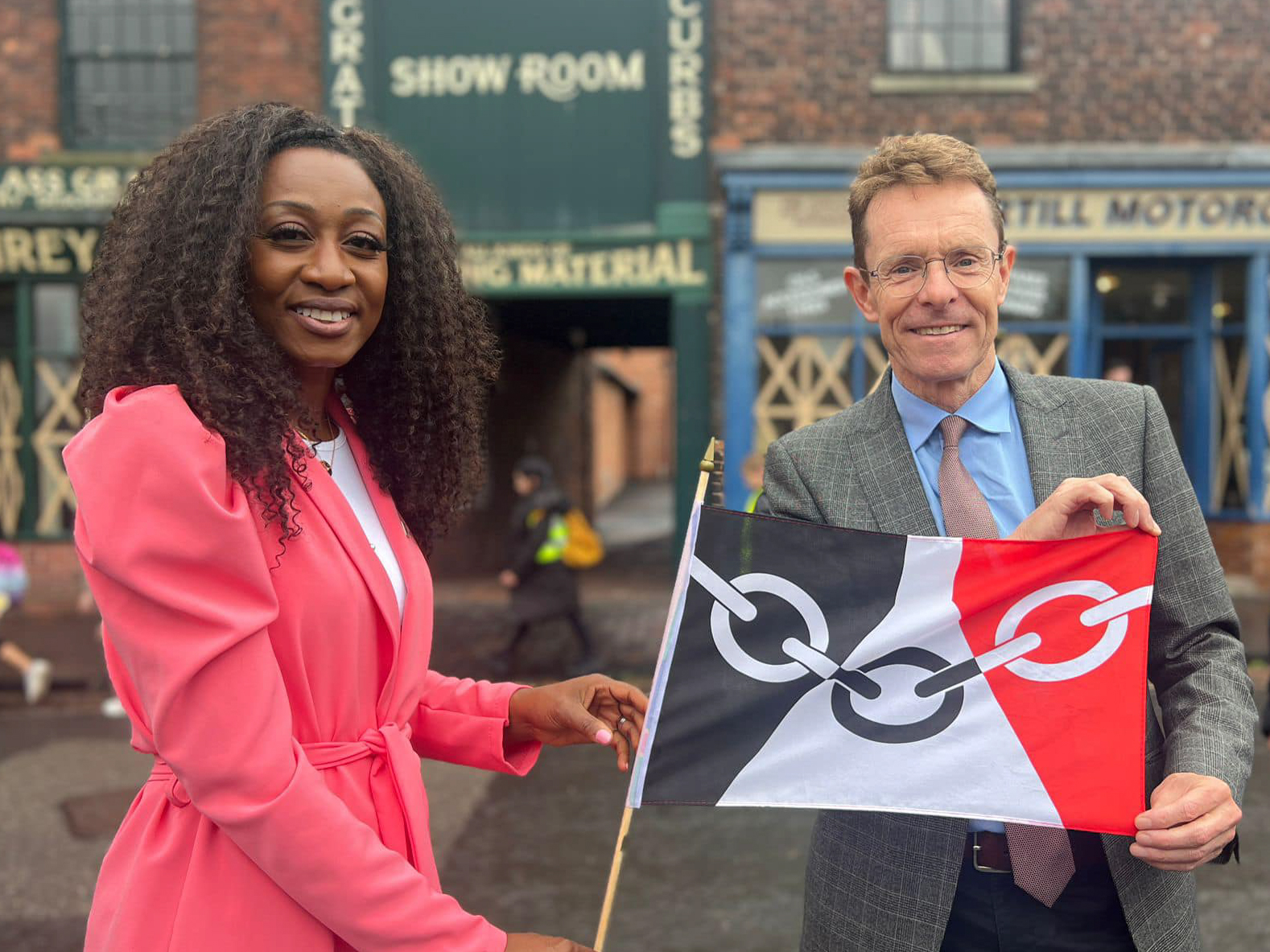 Andy Street and Beverley Knight smiling at the camera holding a Black Country flag at the Black Country Museum