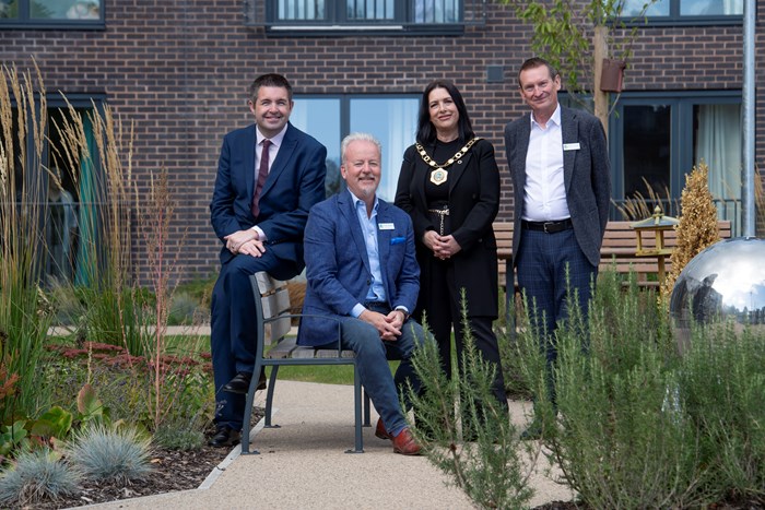 Four people, one sitting three standing outside a housing development in Stirchley