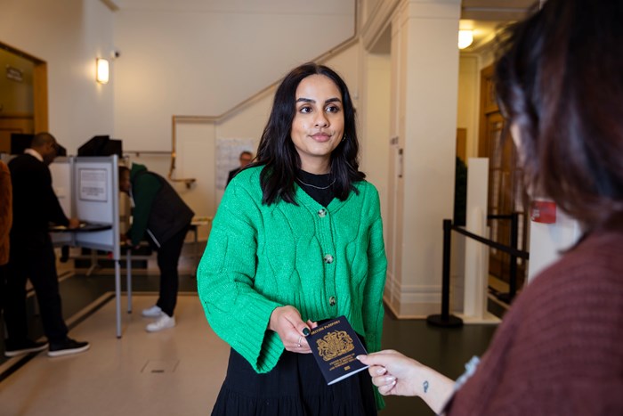A woman showing her passport as ID at a voting centre