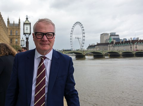The Mayor smiling at the camera with the River Thames, Big Ben and the Houses of Parliament in the background.