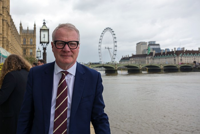 The Mayor smiling at the camera with the River Thames, Big Ben and the Houses of Parliament in the background.