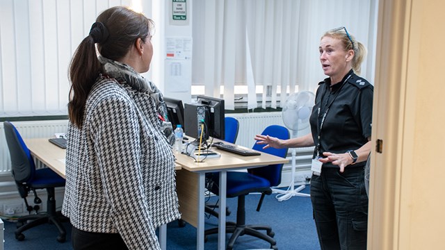 Two women in an office mid discussion. One person is wearing a uniform,