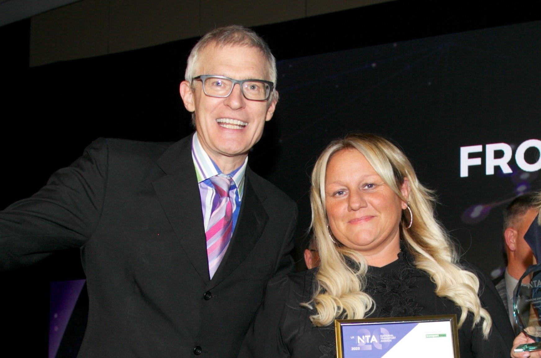 Broadcaster Jeremy Vine presents Kate Evans with her frontline employee of the year award on stage