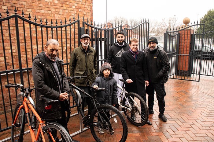 People standing with bikes on bike racks