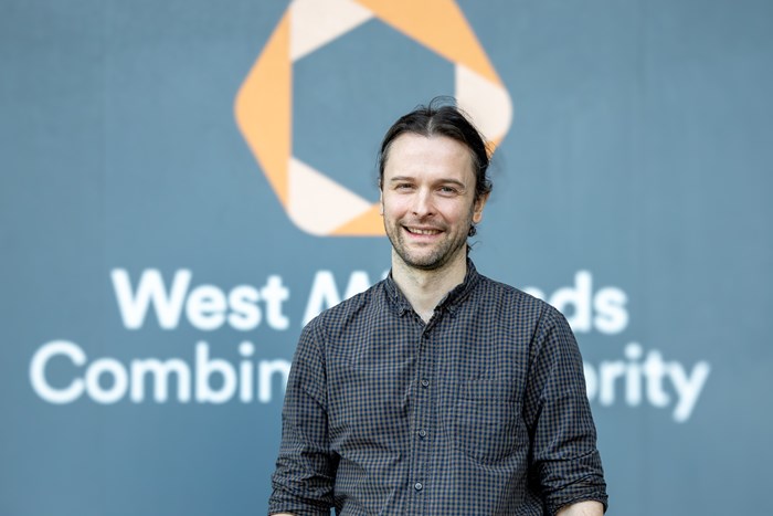 Photograph of a male stood behind a West Midlands Combined Authority logo