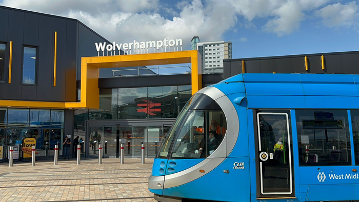 Blue Metro tram outside the distinctive yellow and black entrance to Wolverhampton Railway Station