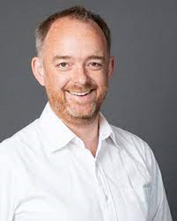A headshot of a man looking down the camera