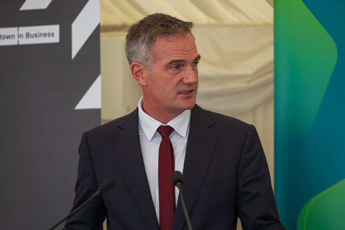 A man speaking at a lectern dressed in formal attire.