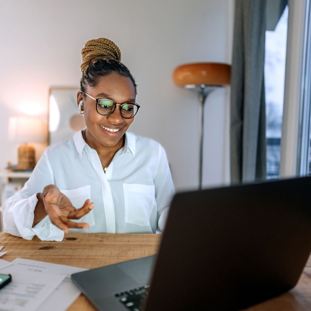 A woman sitting at a desk in her home working on a laptop