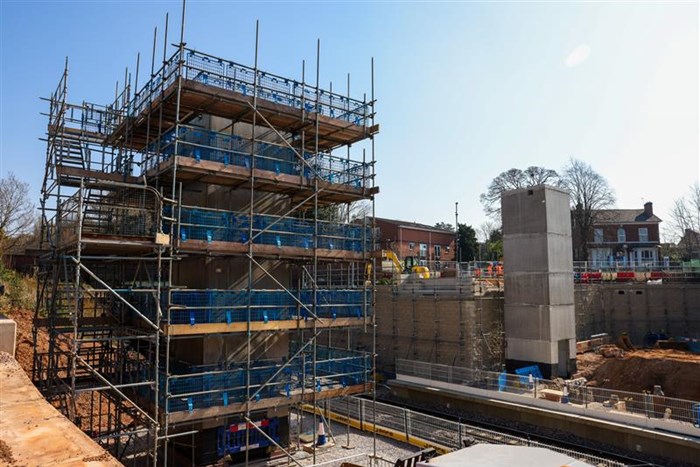 Kings Heath Station site overview with two concrete pillars against a blue sky background. The left pillar, which will be a lift shaft is wrapped in scaffolding.