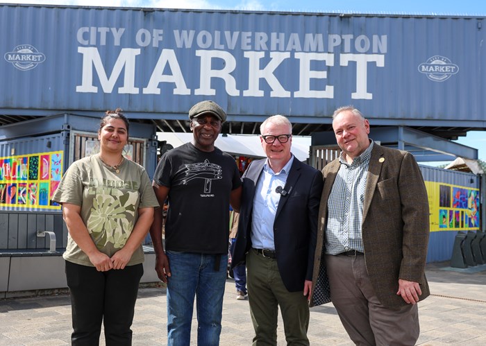 Group of people looking at the camera and smiling with a City of Wolverhampton Market sign in the background