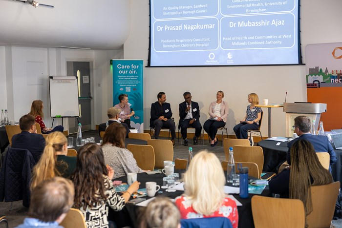 An image of a diverse panel answering questions to a room is full of attendees at the West Midlands Air Quality Conference.