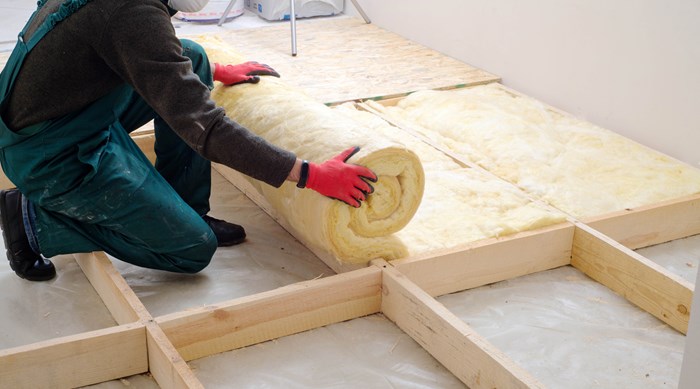 A person laying loft insulation