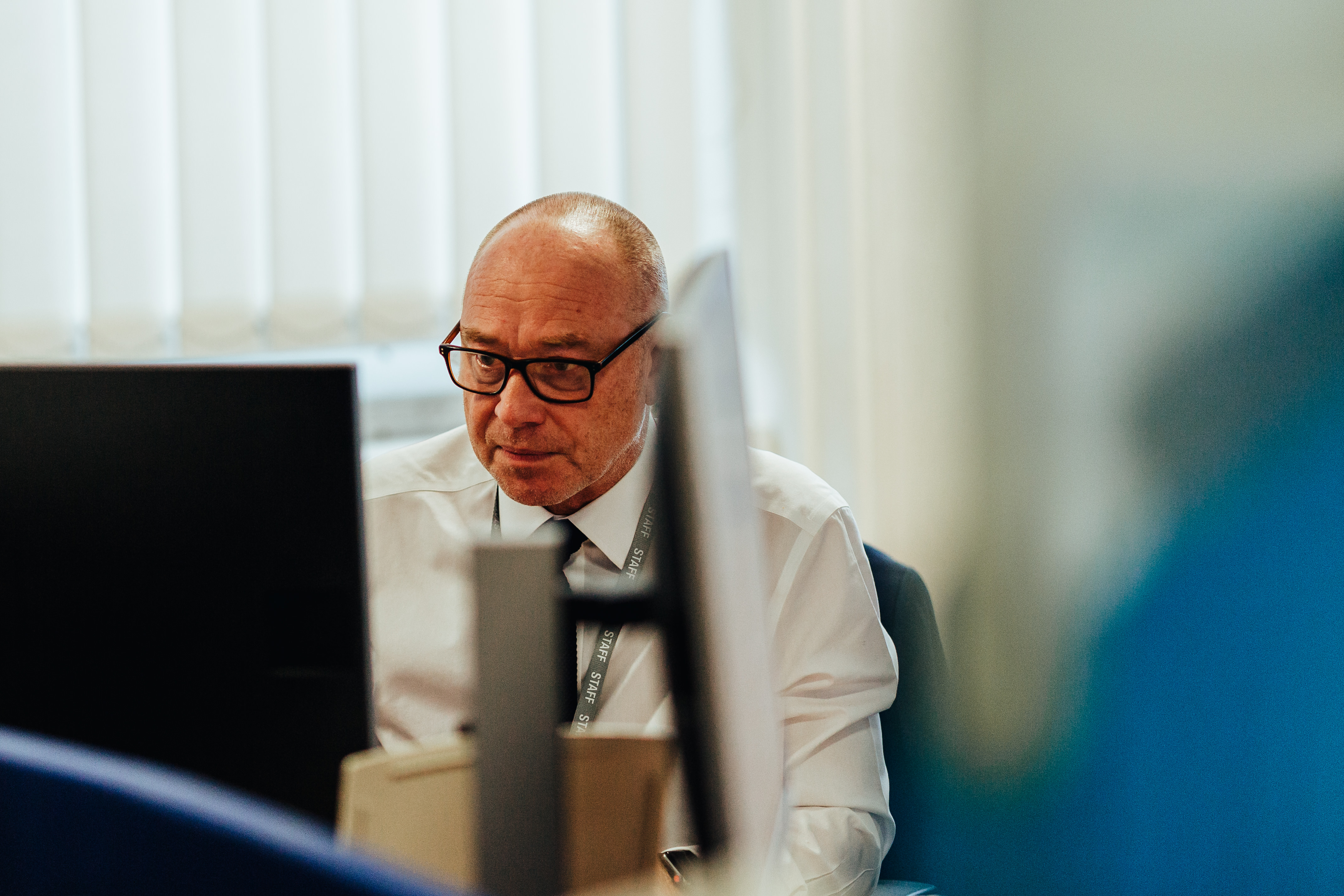 A man wearing glasses working at a computer screen.