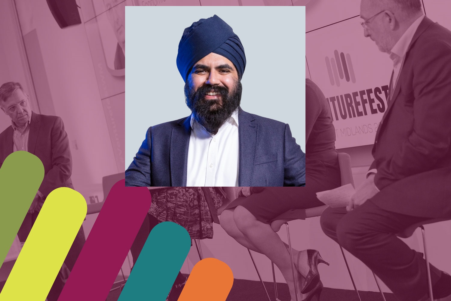 Smiling man with a beard and navy turban, wearing a white shirt and dark blazer, standing against a light gray background. Confident and approachable.