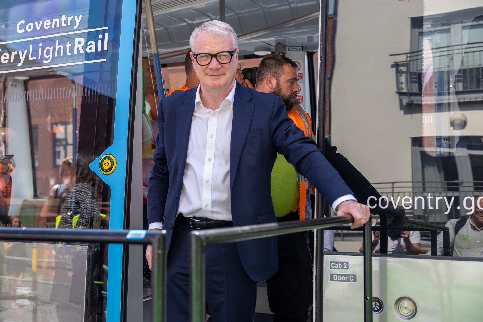 The Mayor is standing in the doorway of a Very Light Rail vehicle