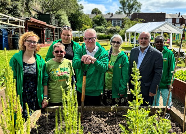 Group of people in a garden with tools in green uniform