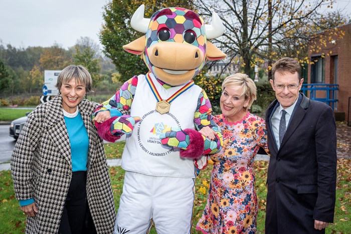 Three people and a bull mascot smiling at the camera.