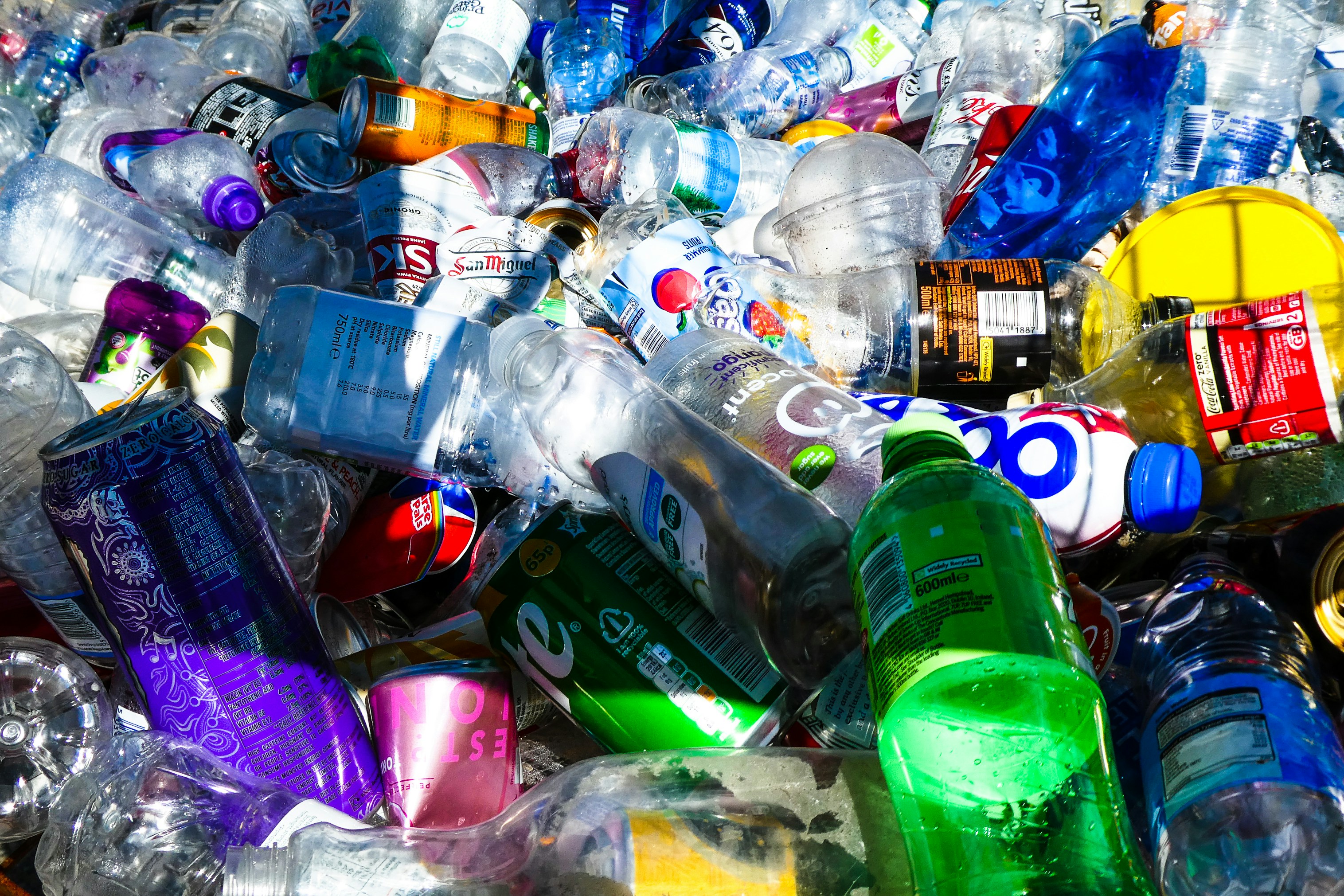 A pile of plastic bottled and different coloured can