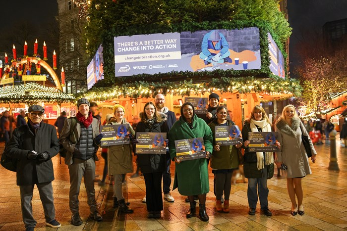 A line up of people looking at the camera in front of a Christmas tree and market stalls