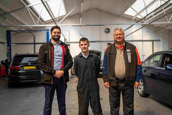 Ben (centre) at his place of work, with Rehal Autohaus owner Tej Rehal his son Amar , standing in a car garage