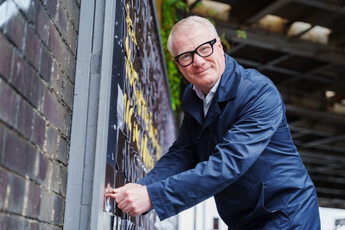 West Midlands Mayor Richard Parker placing the removable bus ticket on the billboard