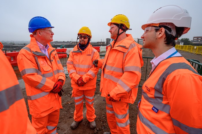 Three  apprentices in orange hi-visibility construction kit talk to mayor Richard Parker at the Curzon Street site