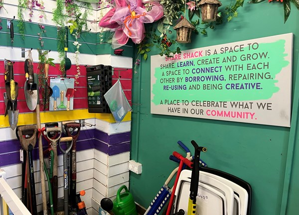 A colourful wall with gardening tools hung up