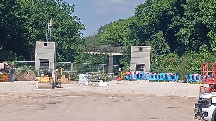 Construction site with the tops of twin towers - the lift shafts - in place and a bridge in the background